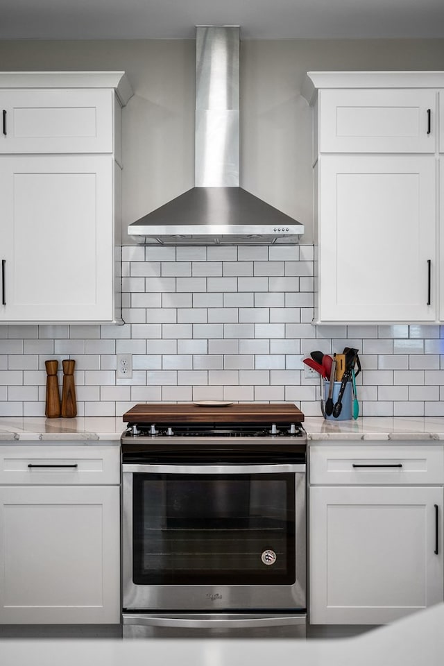 kitchen featuring electric stove, wall chimney range hood, white cabinetry, and decorative backsplash