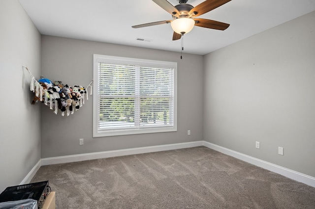 unfurnished room with carpet floors, visible vents, ceiling fan, and baseboards