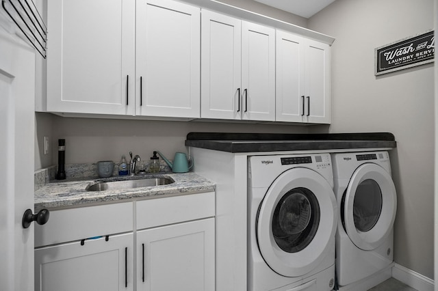 washroom with baseboards, a sink, cabinet space, and washer and dryer