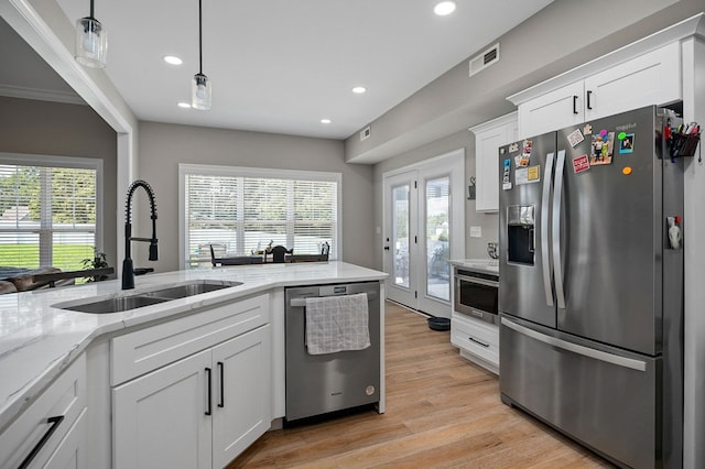 kitchen with visible vents, light stone countertops, stainless steel appliances, white cabinetry, and a sink