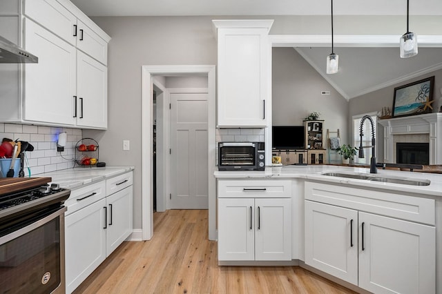 kitchen featuring a fireplace, vaulted ceiling, a sink, light wood-type flooring, and wall chimney exhaust hood