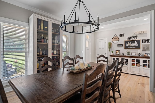 dining area with light wood-type flooring, ornamental molding, a notable chandelier, and recessed lighting