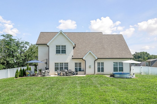 back of house with a shingled roof, a patio area, a fenced backyard, and a lawn