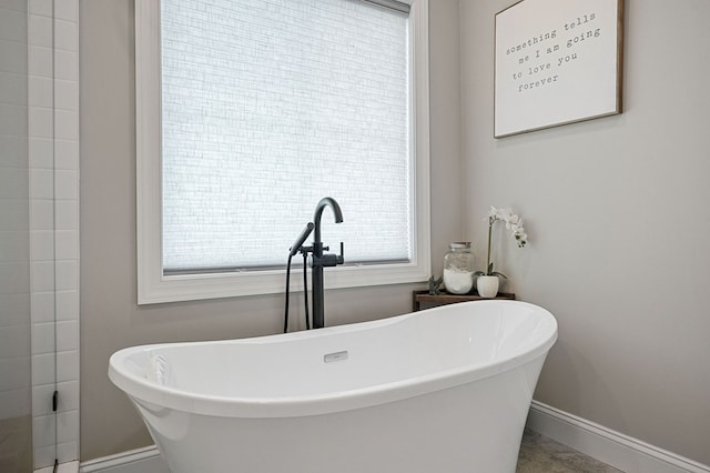 full bathroom featuring a freestanding tub, a sink, and baseboards