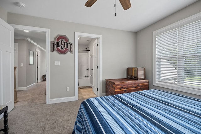 bedroom with light colored carpet, ceiling fan, ensuite bath, and baseboards