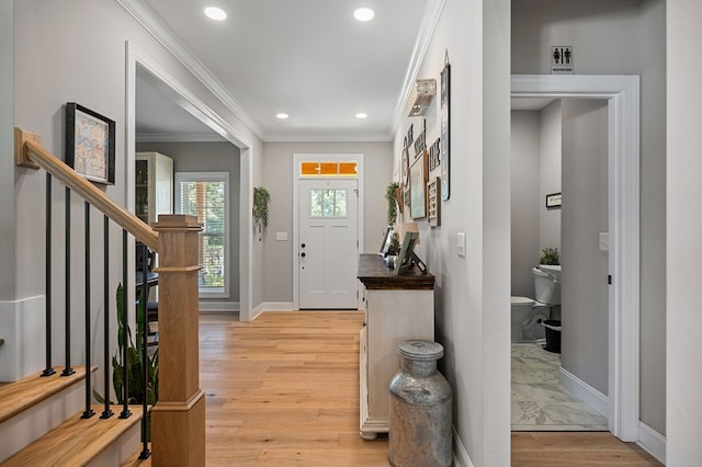 foyer with light wood-style floors, baseboards, stairs, and ornamental molding