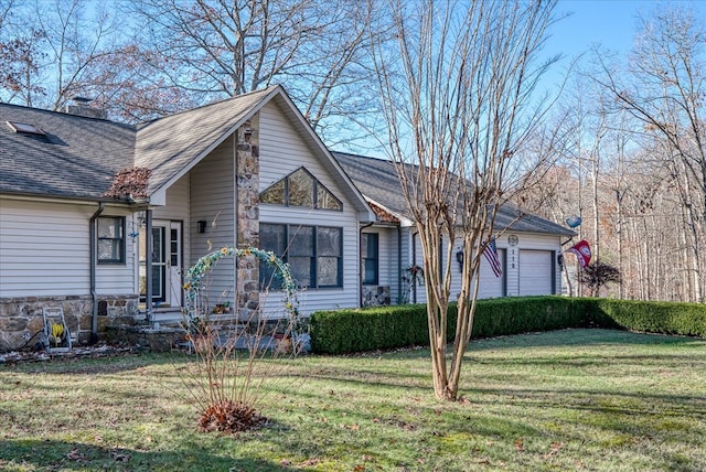 view of front of home with an attached garage, a shingled roof, and a front lawn