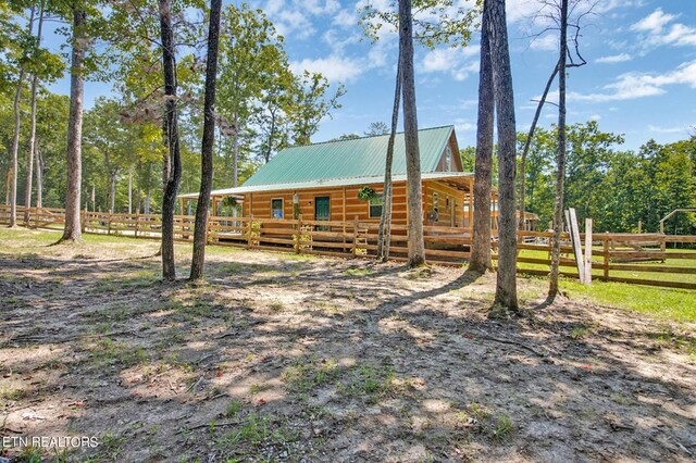 exterior space with an outbuilding, metal roof, log exterior, and an exterior structure