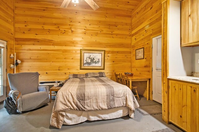 bedroom featuring concrete flooring and wood walls