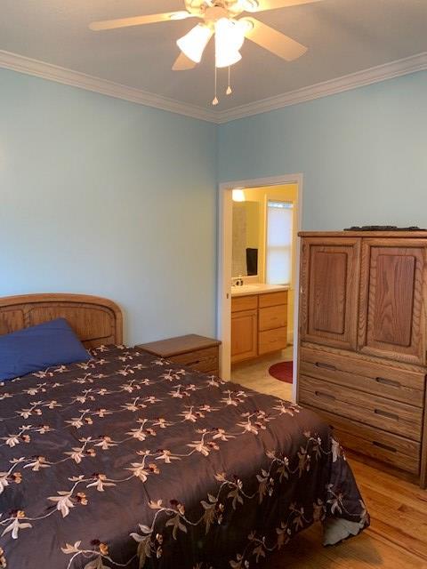 bedroom featuring crown molding, light wood-style flooring, and ensuite bath