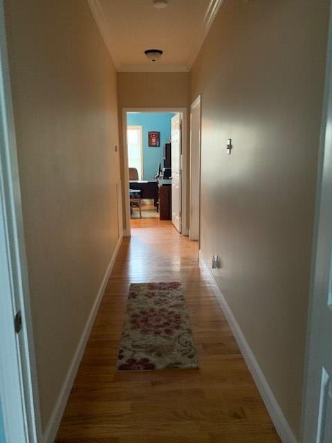 corridor featuring baseboards, light wood-style floors, and crown molding