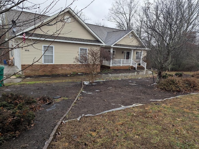 view of front of property featuring a porch, brick siding, and a shingled roof