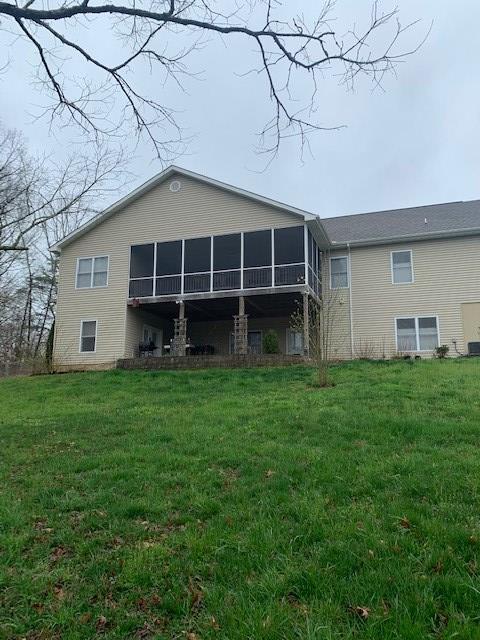 rear view of property featuring a sunroom and a yard