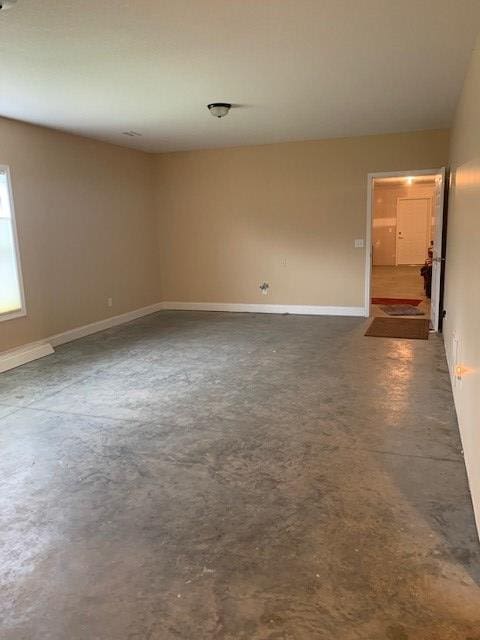 unfurnished room with concrete floors and baseboards