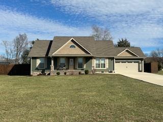 view of front of home with a garage, fence, a front lawn, and concrete driveway