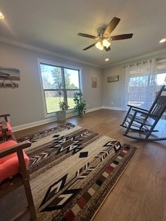 living area with crown molding, baseboards, and wood finished floors