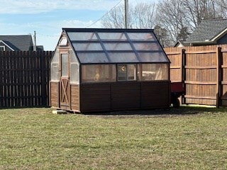 rear view of property with an outbuilding, a fenced backyard, and an exterior structure