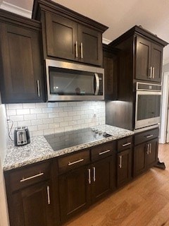 kitchen featuring light stone counters, stainless steel appliances, tasteful backsplash, light wood-style floors, and dark brown cabinetry