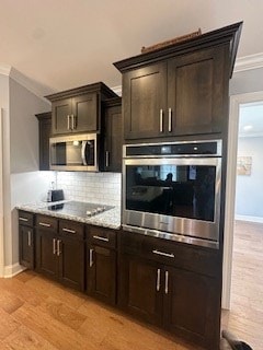 kitchen featuring stainless steel appliances, ornamental molding, dark brown cabinets, and decorative backsplash