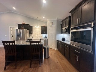 kitchen featuring appliances with stainless steel finishes, lofted ceiling, a kitchen island, and a breakfast bar