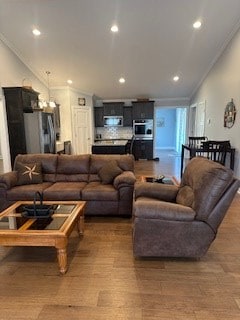 living room featuring lofted ceiling, ornamental molding, and wood finished floors