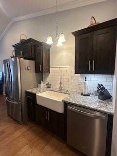 kitchen featuring light stone counters, stainless steel appliances, backsplash, a sink, and wood finished floors