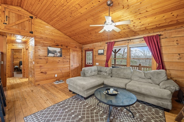 living area with ceiling fan, wooden walls, wood finished floors, wood ceiling, and vaulted ceiling