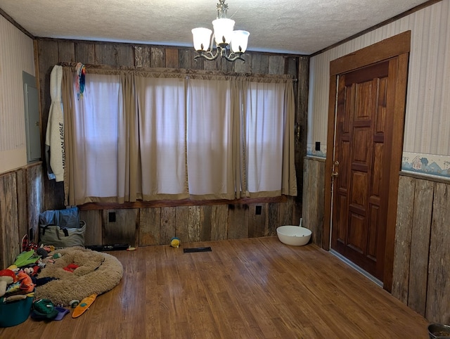 dining area with a textured ceiling, ornamental molding, wood finished floors, and a notable chandelier