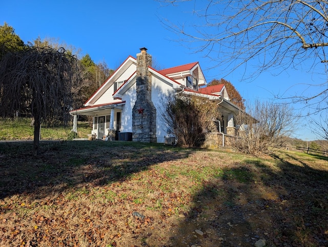 exterior space featuring a front yard, covered porch, central AC, and a chimney