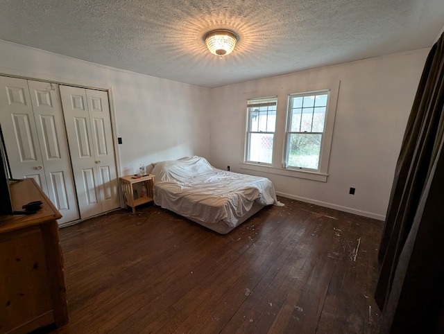 bedroom featuring dark wood-style floors, a closet, a textured ceiling, and baseboards