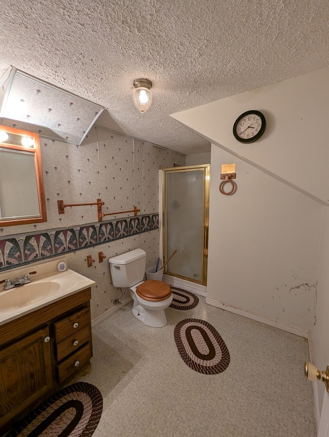 full bath with wallpapered walls, a stall shower, toilet, a textured ceiling, and vanity