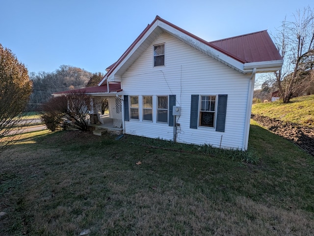 back of house with metal roof and a yard