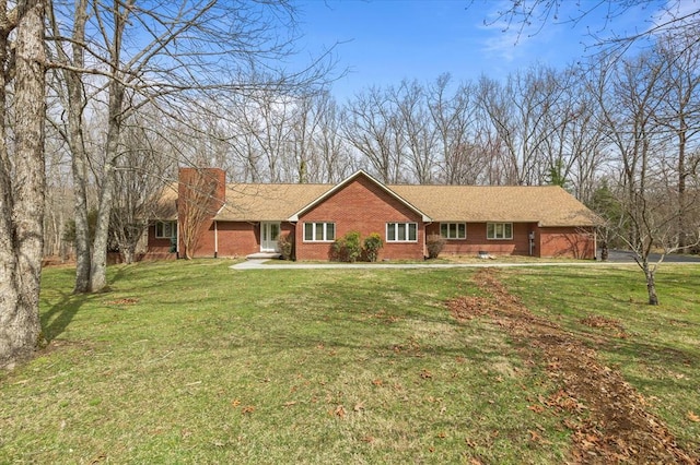 ranch-style home featuring brick siding, a chimney, and a front lawn