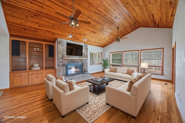 living area with light wood-type flooring, a ceiling fan, a stone fireplace, baseboards, and wood ceiling