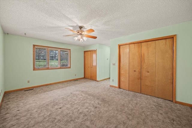 unfurnished bedroom featuring visible vents, baseboards, carpet, and a ceiling fan