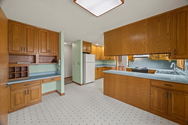 kitchen featuring electric range, a sink, built in desk, freestanding refrigerator, and extractor fan