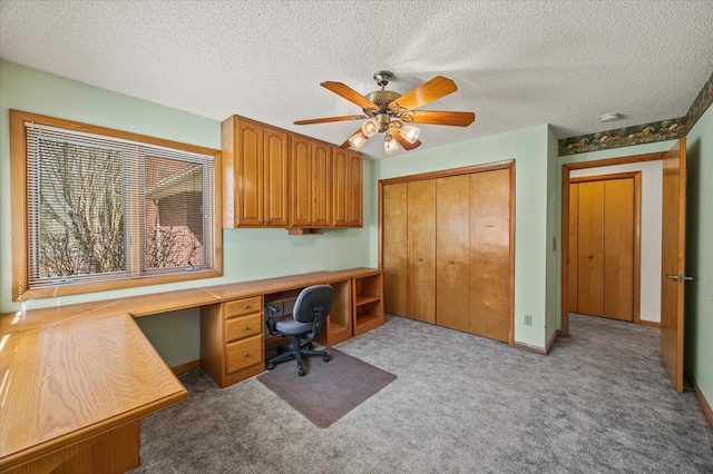 office with baseboards, built in study area, a textured ceiling, and carpet