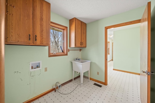 laundry room featuring visible vents, baseboards, washer hookup, cabinet space, and a textured ceiling