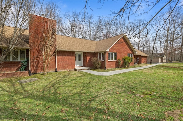 ranch-style house with brick siding, a chimney, a front yard, and roof with shingles