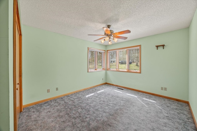 spare room with visible vents, a textured ceiling, carpet, baseboards, and ceiling fan