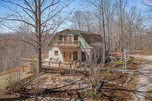 back of property featuring a deck, a gambrel roof, and a balcony