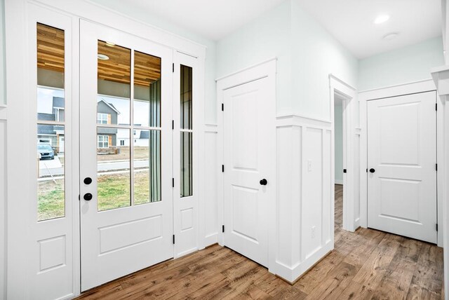 entryway with light wood-style floors, a decorative wall, and wainscoting