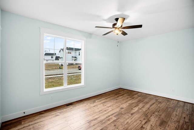 spare room featuring ceiling fan, baseboards, and wood finished floors