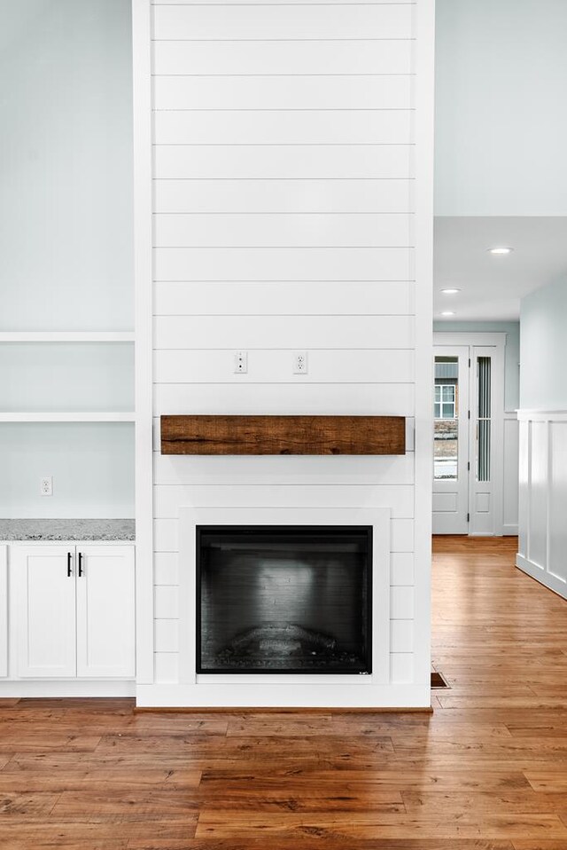 room details featuring a large fireplace, visible vents, and wood finished floors