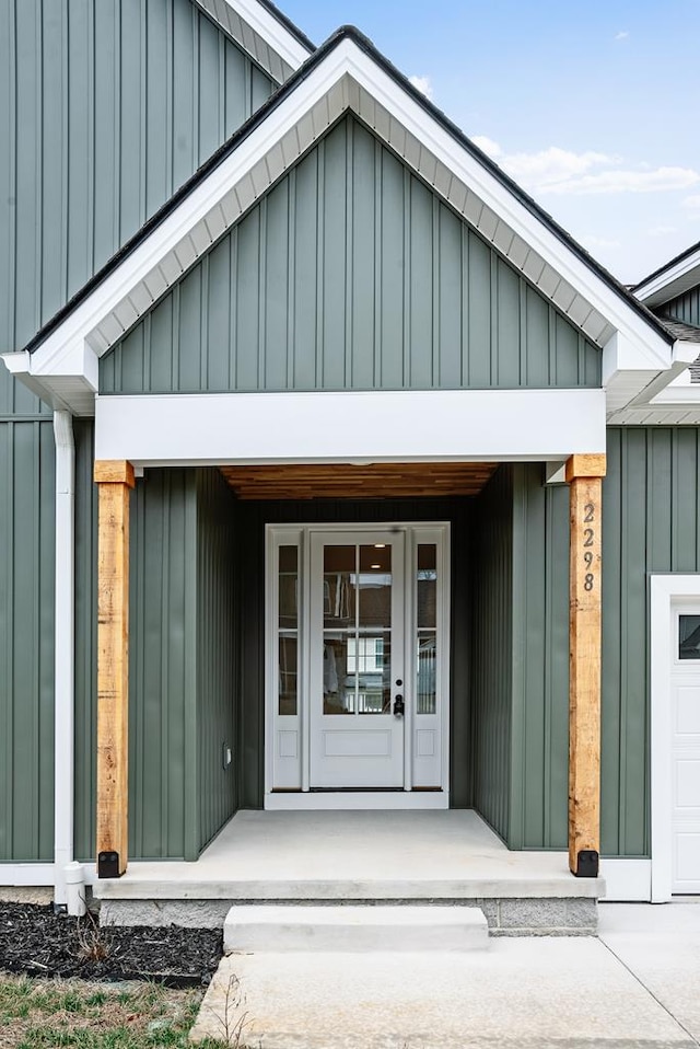 doorway to property with a garage, a porch, and board and batten siding