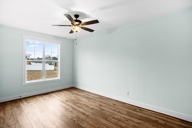 spare room featuring a ceiling fan, baseboards, and wood finished floors