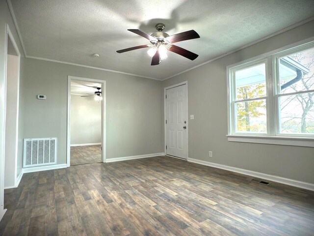 unfurnished room featuring a textured ceiling, visible vents, dark wood-type flooring, and ornamental molding