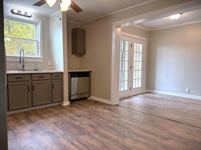 kitchen featuring dark wood finished floors, light countertops, stainless steel dishwasher, ornamental molding, and a sink