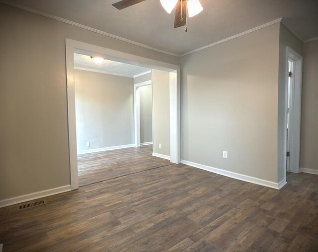 empty room featuring ornamental molding, dark wood finished floors, and visible vents