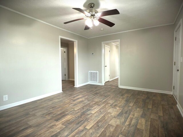 unfurnished room with dark wood-style flooring, crown molding, visible vents, a ceiling fan, and baseboards